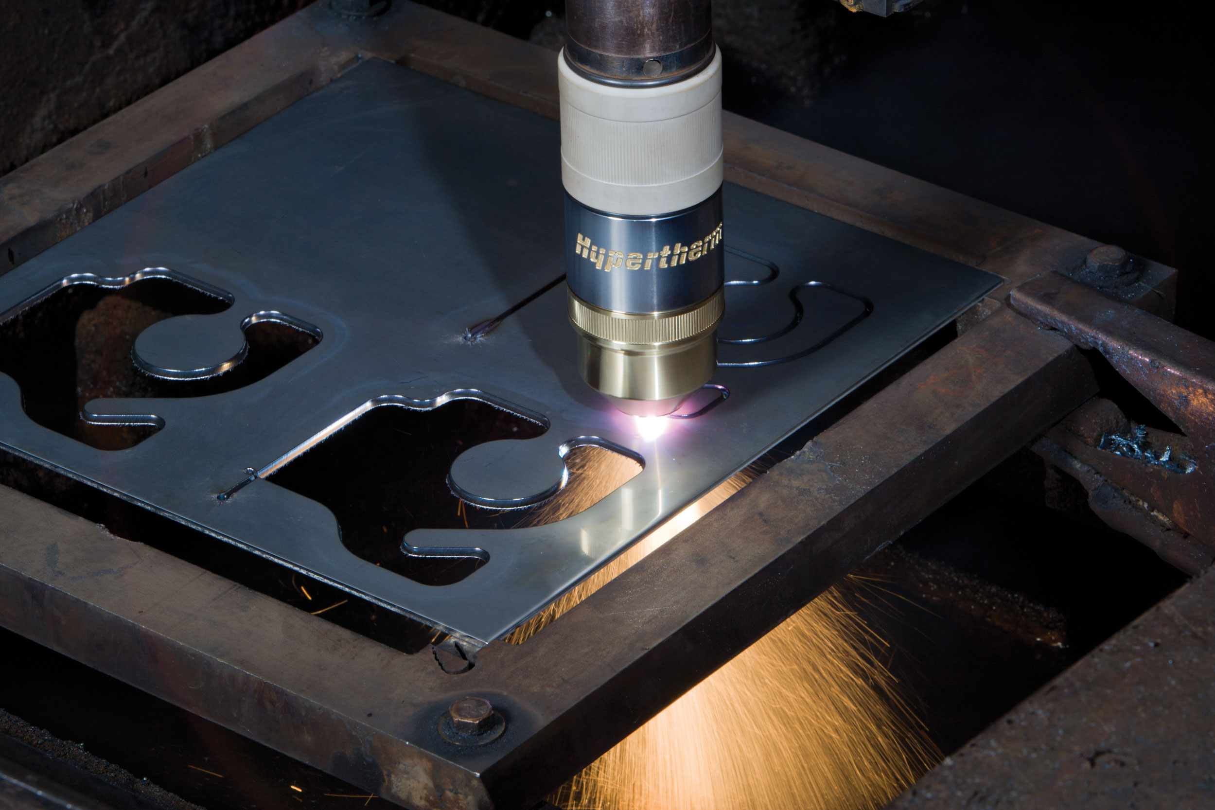 A CNC plasma cutting machine cutting pieces from a steel sheet.